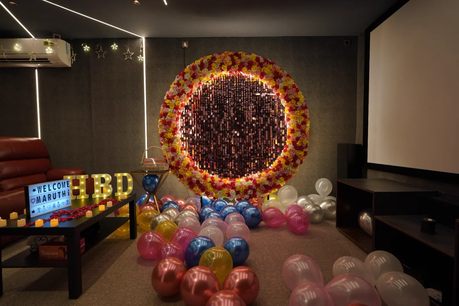 Sample private cinema setup with projection screen, lounge seating, feature lighting and birthday decoration