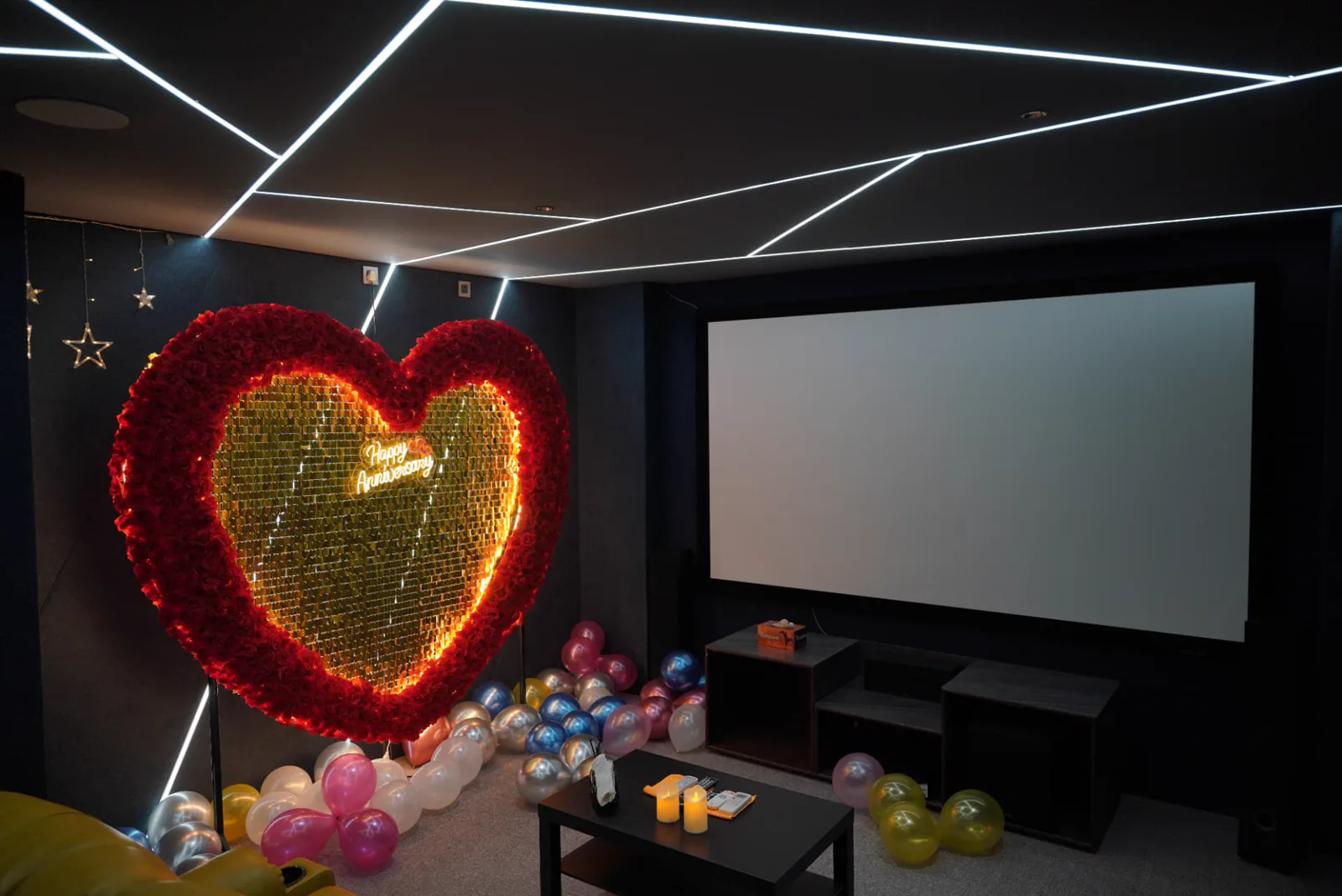 Private screening room sample with projection screen, geometric ceiling lights, balloons and anniversary décor
