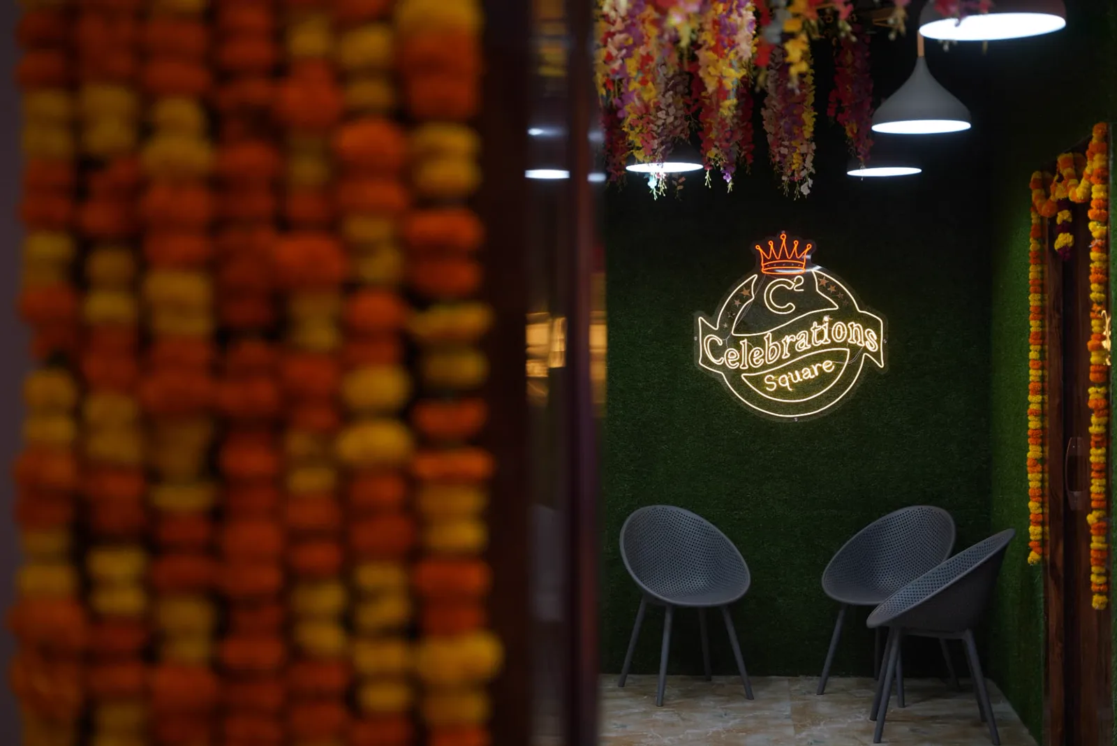Sample welcome lounge with floral ceiling décor, pendant lighting and branded illuminated wall sign