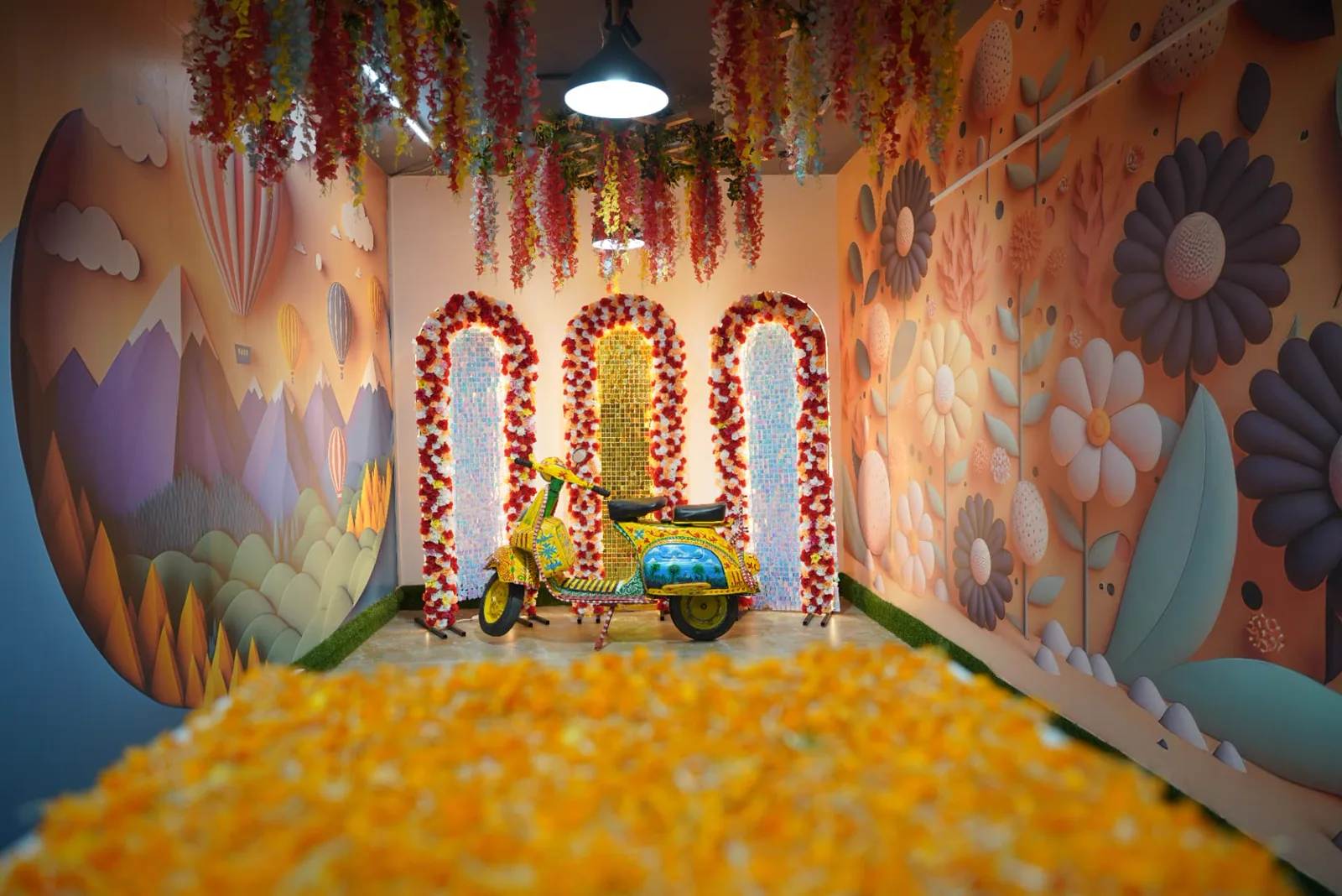 Sample themed celebration hall with floral ceiling treatment, illustrated walls and a decorated scooter display