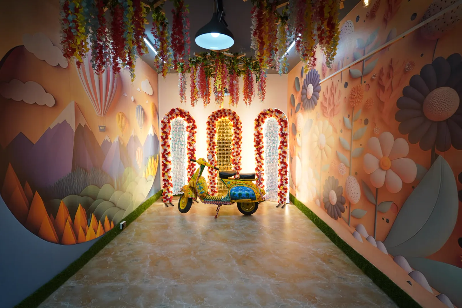 Sample colourful private celebration room with illustrated walls, hanging flowers and a decorated scooter